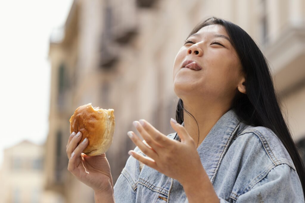 Seorang wanita makan roti yang merupakan salah satu menu wajib continental breakfast